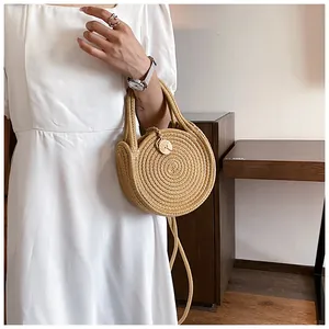 Détail d'un sac rond en paille tressée avec pendentif soleil et bandoulière amovible