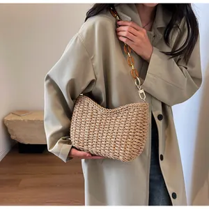 Detalle del bolso de paja trenzado con cadena de acrílico ámbar y ganchos dorados