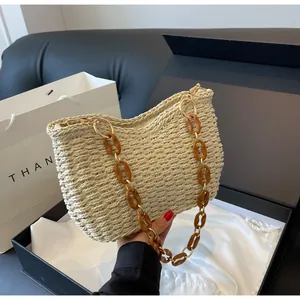 Detalle del bolso de paja con cadena de resina ámbar y hebilla metálica dorada