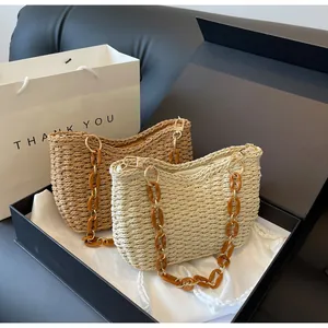 Detalle de bolso de paja trenzada con cadena de acrílico ámbar y cierre dorado