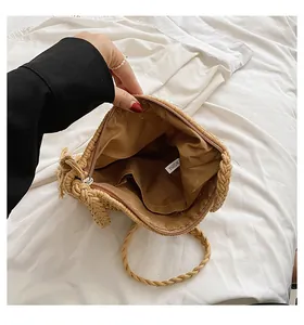 Detail view of woven straw bag interior with zipper closure and brown lining for beach use
