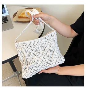 Detail of white macrame woven phone bag with dense diamond patterns and fringe trim