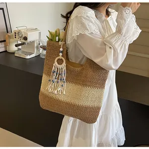 Detail of bohemian straw tote bag featuring multi-color stripes and evil eye tassel charm