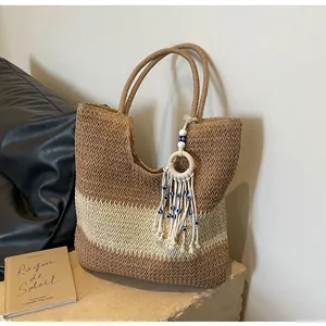 Close-up of woven straw tote bag with evil eye tassel and natural texture detail