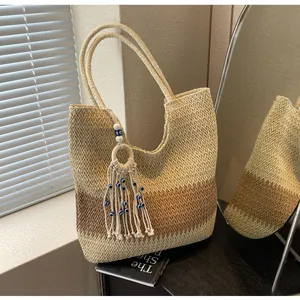 Detail of bohemian woven straw tote bag featuring contrast colors and evil eye tassel charm