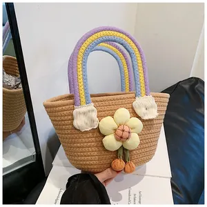 Détail du sac à main en paille avec anses arc-en-ciel et breloque fleurie jaune