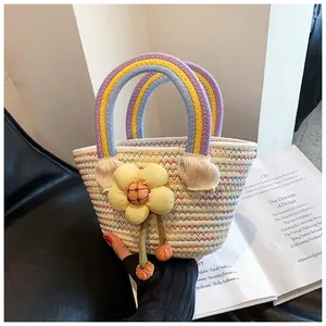 Détail du sac tressé avec poignée arc-en-ciel et breloque fleur jaune géante