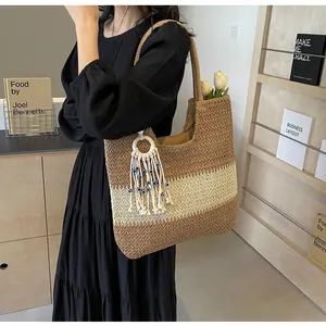 Detail of bohemian straw tote with three-tone patchwork and evil eye tassel charm