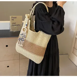 Detail of bohemian straw tote bag with color blocking and stylish evil eye tassel pendant