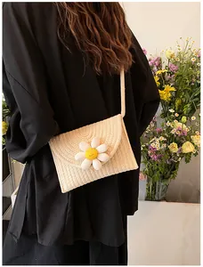 Détail du sac carré en paille tissée avec une marguerite 3D et un motif de visage souriant