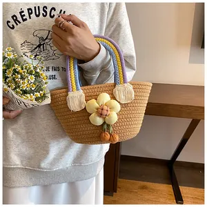 Détail du sac cabas en paille tressée avec poignées colorées et décoration florale 3D