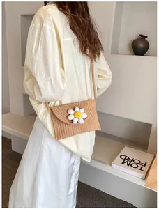 Détail du sac bandoulière en paille tissée avec fleur de marguerite et bandoulière
