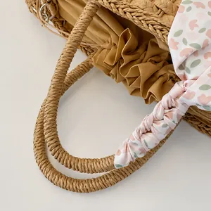 Detalle de bolso de paja tejida con pañuelo de seda floral y forro interior ajustable