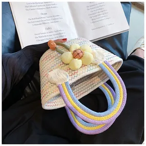 Détail d'un sac tissé en zigzag avec fleur 3D et poignées en corde arc-en-ciel