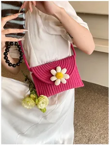 Détail du sac bandoulière tissé rose rouge avec décoration de fleur de marguerite