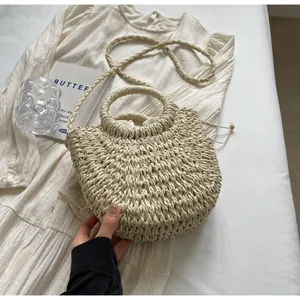 Close-up of woven straw handbag with round handle and inner drawstring on a summer dress