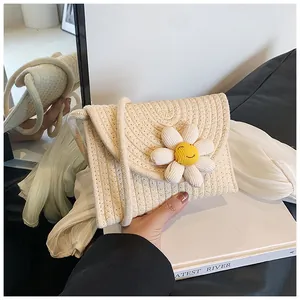 Détail du sac bandoulière tissé avec grande fleur marguerite et motif visage souriant