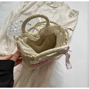 Detail of straw bag featuring white fabric lining, drawstring closure, and inner pocket