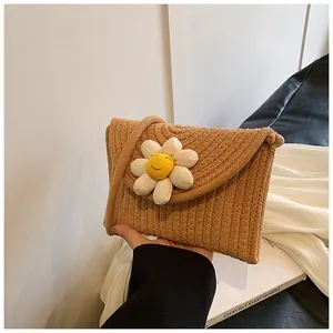 Détail d'un petit sac en paille tressée orné d'une marguerite 3D avec visage souriant