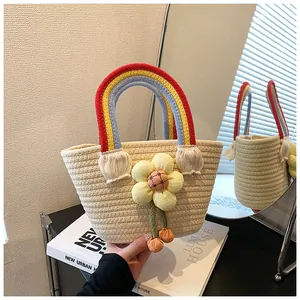 Détail d'un sac cabas tissé main avec anses arc-en-ciel et grande décoration florale