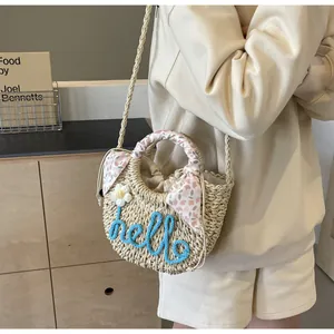 Detail of straw bag with hello embroidery, floral scarf handle, and drawstring lining
