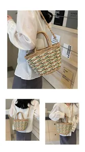 Detail of straw handbag featuring light green spiral stripes and a detachable shoulder strap