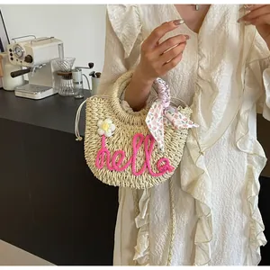Detail of straw handbag with pink hello embroidery and floral scarf on a cafe table