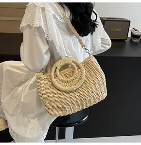 Dettaglio borsa in paglia intrecciata con grande manico rotondo e tracolla stile estivo