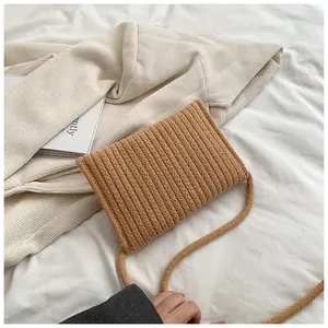 Détail d'un sac bandoulière tissé en paille avec texture sur fond de lin blanc
