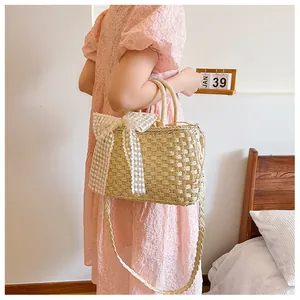 Detalle de bolso de paja trenzada con lazo de encaje grande y bordado elegante