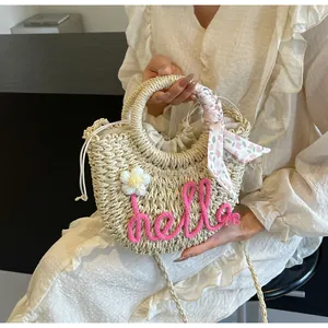 Detail of crescent straw bag with pink hello embroidery and floral scarf handle