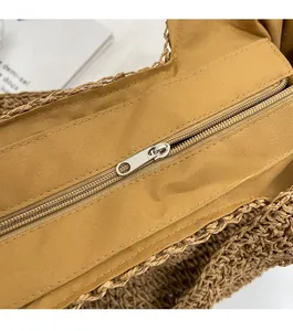 Detailed close-up showing the smooth silver zipper closure on this woven straw beach bag
