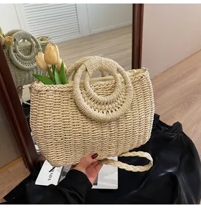 Dettaglio della borsa in paglia beige con manici rotondi e tracolla intrecciata