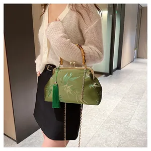 Detailed shot of green silk bag with bamboo embroidery and natural bamboo handle