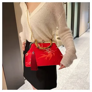 Detail of red satin handbag with bamboo handle, gold embroidery and silk tassel