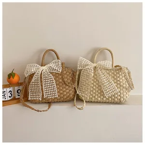Detalle de bolsos de paja tejida con grandes lazos de encaje en caqui y crema