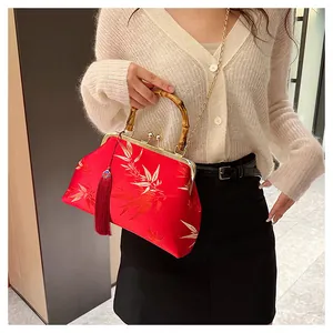 Detailed shot of red satin bag with bamboo handle, gold embroidery, and tassel charm