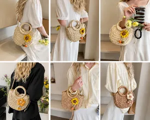 Detail der gewebten Strohtasche mit Blumenakzenten und vielseitigen Trageriemen