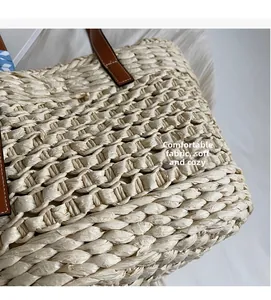 Detail of hand-woven straw tote with brown leather handles and premium stitching