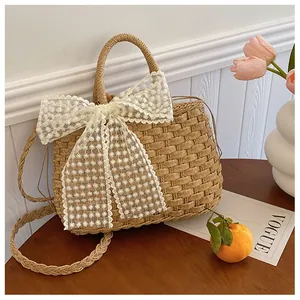 Detalle del bolso de paja con lazo de encaje blanco y bordado floral delicado