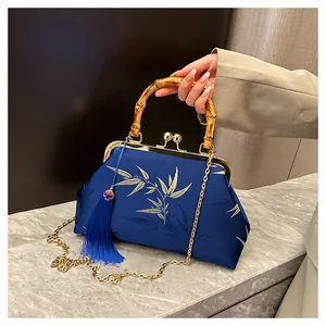 Close-up of bamboo handle and gold bamboo leaf embroidery on blue satin bag