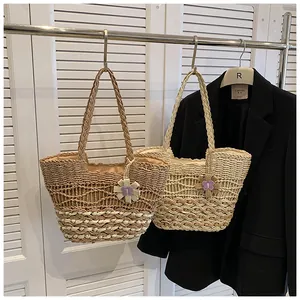 Detail of straw woven tote bags in brown and beige with floral charms on a hanger