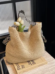 Handgeweven strooien strandtas met zwart-wit gestreepte handvatten op marmeren blad