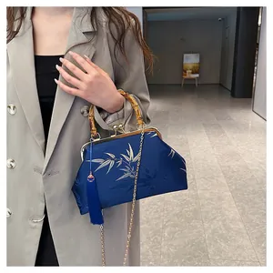 Detail of navy satin bag with silver bamboo embroidery and natural bamboo handle