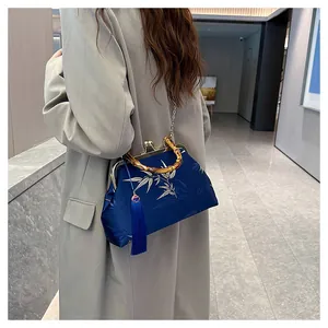 Close-up of traditional embroidery handbag with bamboo handle and blue tassel detail