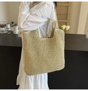 Detail shot of a large straw tote bag with wide straps in a relaxed indoor setting