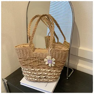 Detail of woven straw tote bag with wave patterns and white floral charm pendant