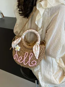 Semi-circular straw crossbody bag with pink hello text and floral scarf handle
