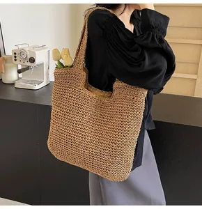 Detail of large woven straw tote bag with wide shoulder strap in a cozy cafe setting