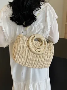 Borsa tote in paglia con manici tondi e tracolla indossata da una modella in luce